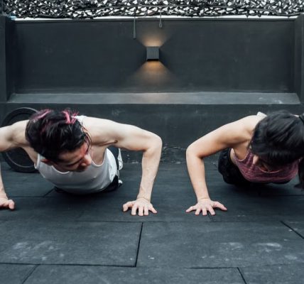 Two adults doing push-ups in an indoor gym setting in Mexico City, promoting a fit and healthy lifestyle.