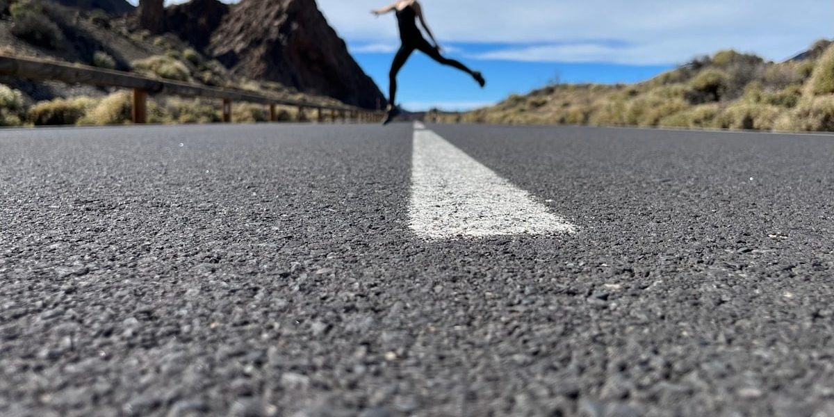 a woman is running down the road in the middle of nowhere