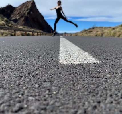 a woman is running down the road in the middle of nowhere