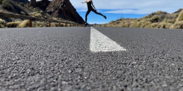 a woman is running down the road in the middle of nowhere