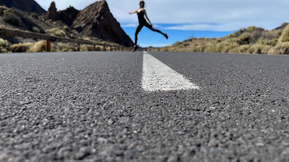 a woman is running down the road in the middle of nowhere